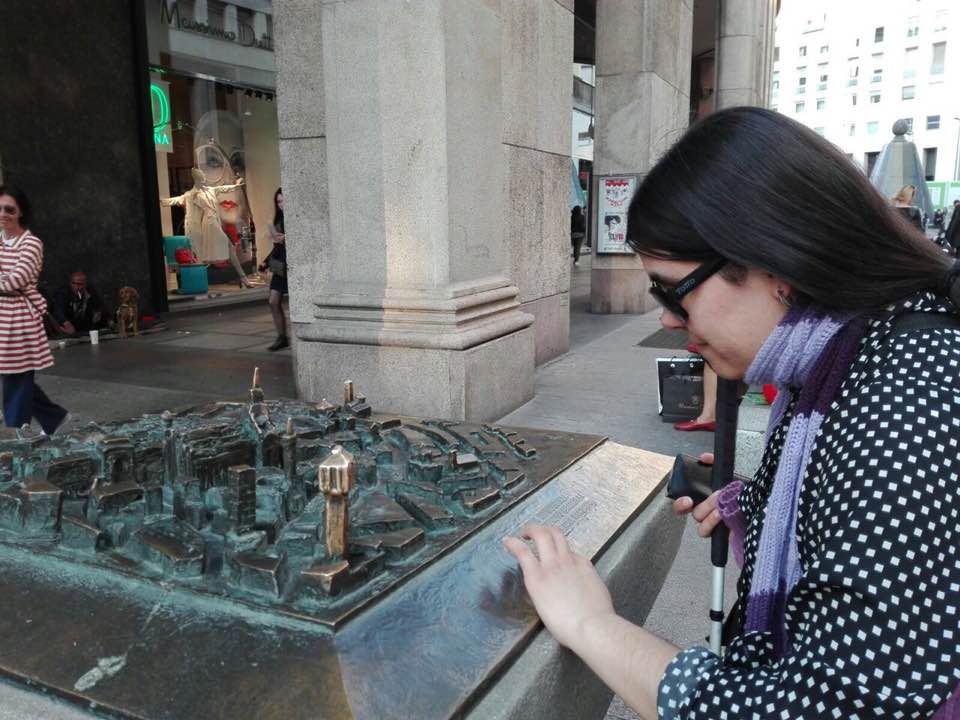 Aprendiendo de la ciudad Milan frente a maqueta en metal a escala leyendo